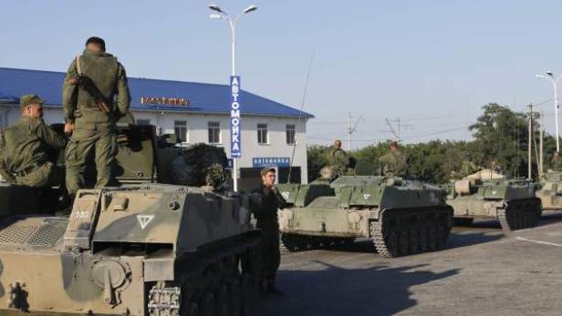Eine Kolonne von Militärfahrzeugen steht auf einer Straße.