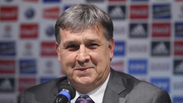 Ein Mann im Anzug spricht in ein Mikrofon vor einer Wand mit Logos.