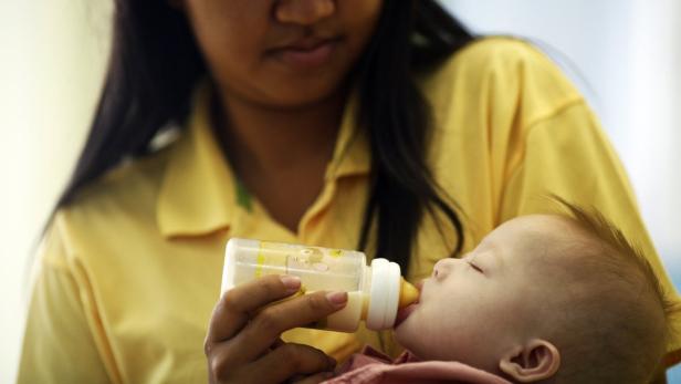 Eine Frau füttert ein Baby mit einer Flasche.