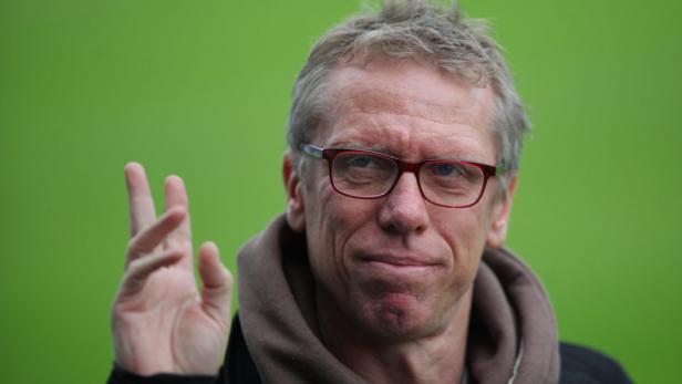Ein Mann mit Brille gestikuliert vor einem grünen Hintergrund.