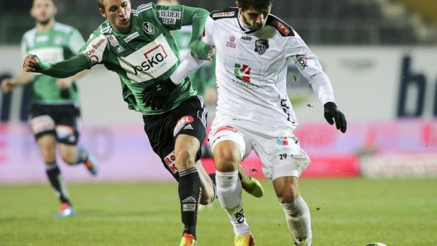 Zwei Fußballspieler kämpfen um den Ball auf dem Spielfeld.
