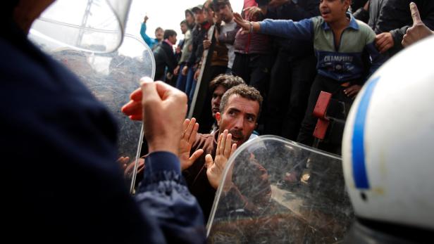 Ein Mann steht vor einer Reihe von Polizisten mit Schutzschilden.