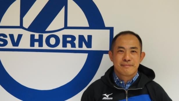 Ein Mann steht vor dem Logo des SV Horn.