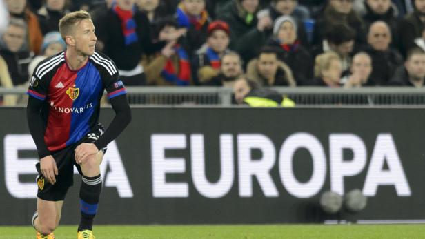 Ein Fußballspieler des FC Basel kniet auf dem Rasen vor einer Werbetafel mit der Aufschrift „Europa“.