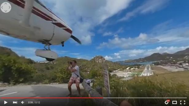 Ein Mann fotografiert ein landendes Flugzeug auf der Insel Saint Martin.