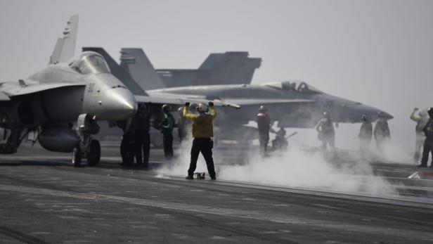 Flugzeuge und Personal auf dem Deck eines Flugzeugträgers.