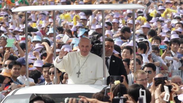 Papst Franziskus winkt einer Menschenmenge zu.