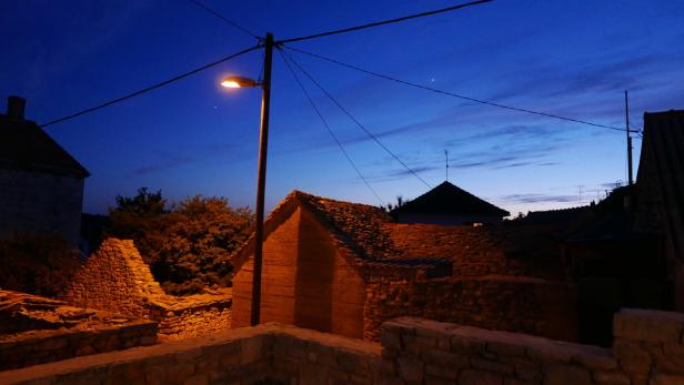 Inselleben: Eine Laterne und die Sterne beleuchten abends die enge Gasse in Srednje Selo
