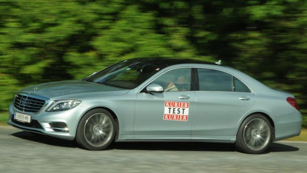 Ein silberner Mercedes-Benz mit einem „Kurier Test“-Aufkleber fährt auf einer Straße.
