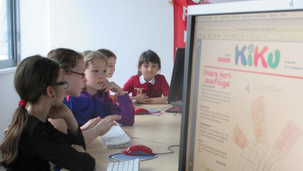 Eine Gruppe von Kindern sitzt vor einem Computer und betrachtet die Webseite „KiKu“.