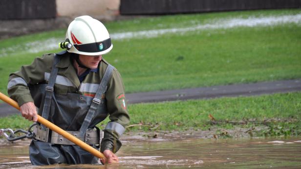 Ein Feuerwehrmann inmitten eines überfluteten Bereiches in Feldbach.