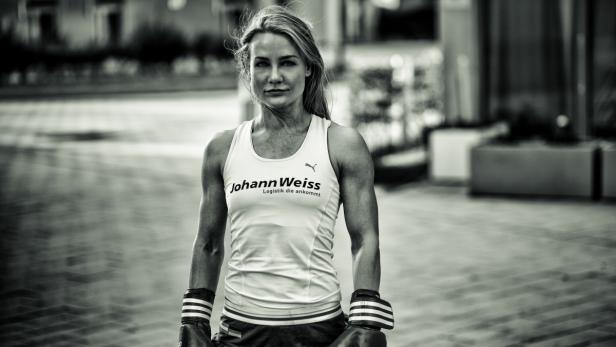 Eine Frau mit Boxhandschuhen und einem Sporttop mit dem Logo von Johann Weiss Logistik.