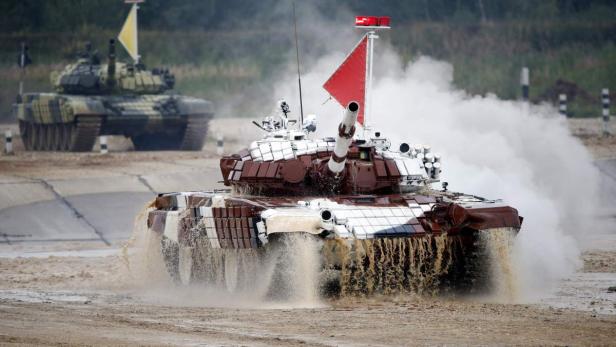Ein braun-weiß gestreifter Panzer fährt durch eine Wasserhindernisstrecke.