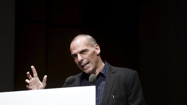 Yanies Varoufakis hält eine Rede vor einem dunklen Hintergrund.