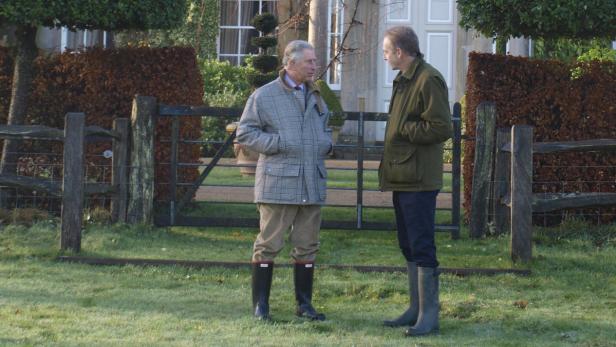 König Charles III. unterhält sich im Garten mit einer anderen Person.
