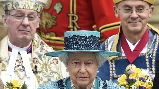 Königin Elisabeth II. trägt einen hellblauen Hut mit dunkler Spitze.