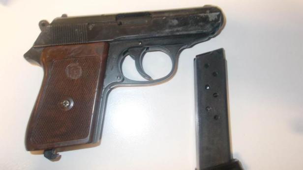 Eine Pistole mit herausgenommenem Magazin liegt auf einem Tisch.