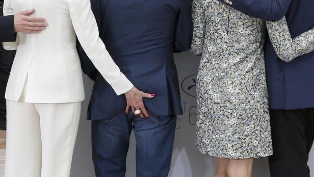 Eine Frau berührt den Hintern eines Mannes vor einer Wand mit dem Logo der Filmfestspiele von Cannes.
