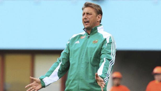 Ein Trainer gestikuliert während eines Fußballspiels.