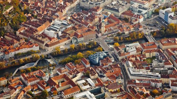 Luftaufnahme von Graz mit dem Fluss Mur und dem Kunsthaus Graz.