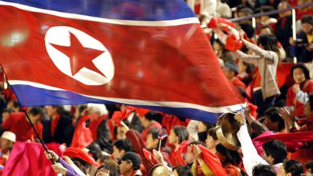 Eine Menschenmenge jubelt mit der nordkoreanischen Flagge.