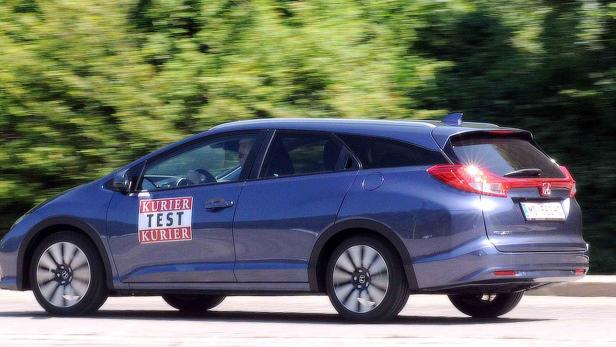 Ein blauer Honda Civic Kombi mit „Kurier Test Kurier“-Aufklebern fährt auf einer Straße.