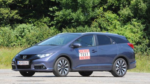 Ein blauer Honda Civic Kombi steht vor einer grünen Baumreihe.