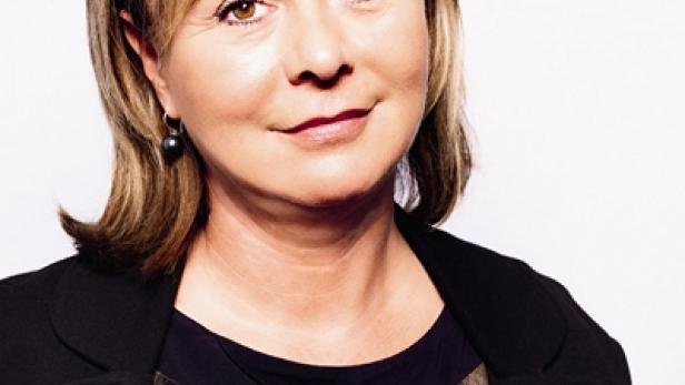 Porträt einer Frau mit blonden Haaren, die eine dunkle Jacke trägt.
