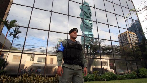 Ein uniformierter Wachmann steht vor einem Gebäude, dessen Fenster einen Wolkenkratzer reflektieren.
