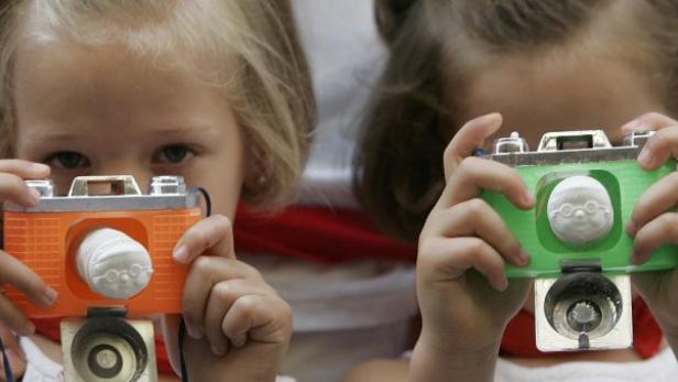Zwei kleine Mädchen fotografieren mit Spielzeugkameras.