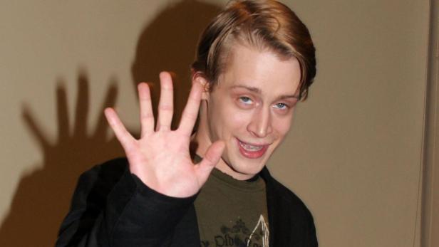 Macaulay Culkin winkt mit der Hand in die Kamera.