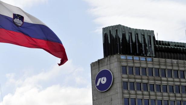 Slovenia's national flag flutters next to NLB buil Die slowenische Flagge weht vor einem Bürogebäude mit einem runden Logo.