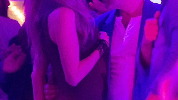 Eine Frau umarmt einen Mann auf einer Party mit violetter Beleuchtung.