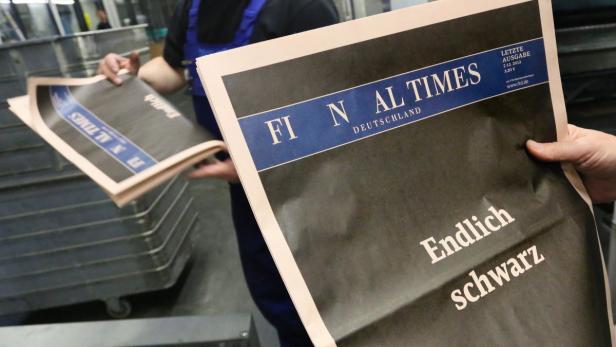 epa03499330 A worker holds a copy of the last edition of the Financial Times Deutschland (FTD) at a printing plant in Berlin, Germany, 06 December 2012. Its closure brings to an end the newspaper&#039;s 12-year publishing history. It was previously the German offshoot of London&#039;s Financial Times. EPA/STEPHANIE PILICK