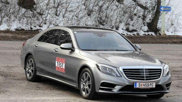 Eine graue Mercedes-Benz Limousine mit einem „Kurier Test Kurier“-Aufkleber auf der Tür.