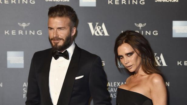David und Victoria Beckham posieren auf einer Veranstaltung vor Logos von Kering und Swarovski.