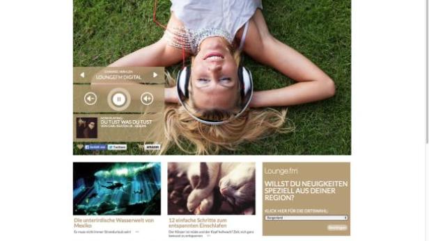 Eine Frau liegt entspannt im Gras und hört Musik über Kopfhörer.