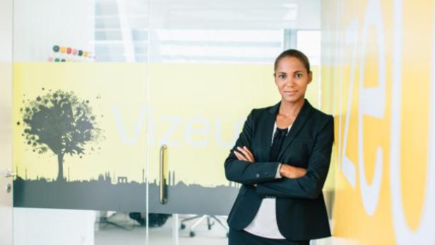 Eine Frau im Hosenanzug steht vor einer Wand mit dem Schriftzug „Vizeu“.