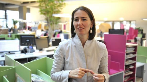 Eine Frau steht in einem Großraumbüro.