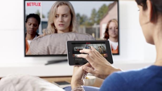 Eine Frau schaut „Orange Is the New Black“ auf einem Tablet, während die Serie auch auf dem Fernseher läuft.