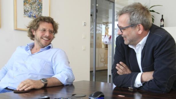 Zwei Männer sitzen an einem Tisch und unterhalten sich.