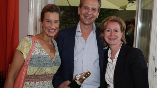 Drei Personen posieren mit einer Champagnerflasche für ein Foto.