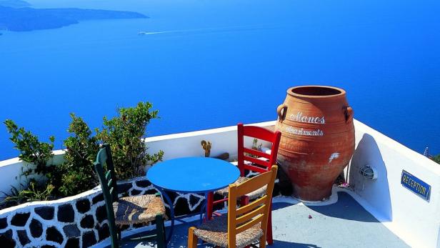 Ein Tisch und Stühle auf einer Terrasse mit Blick auf das Meer in Santorini.