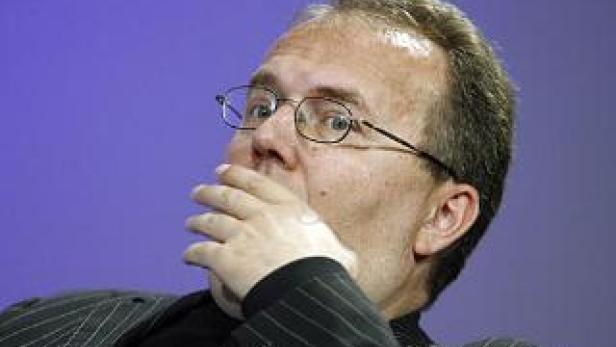 Ein Mann mit Brille hält seine Hand vor den Mund.