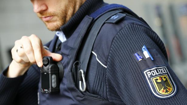 Ein Polizist befestigt eine Bodycam an seiner Uniform.