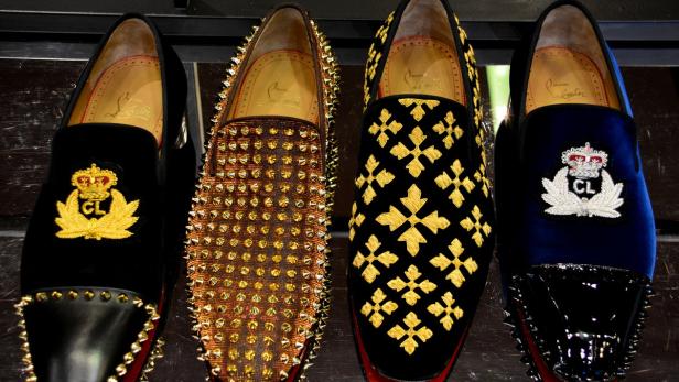 Vier Paar Louboutin-Slipper mit verschiedenen Verzierungen stehen nebeneinander.