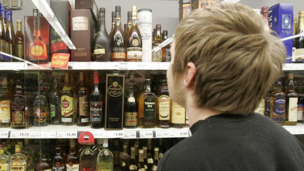 Ein Mann betrachtet eine Auslage mit verschiedenen Spirituosen in einem Geschäft.