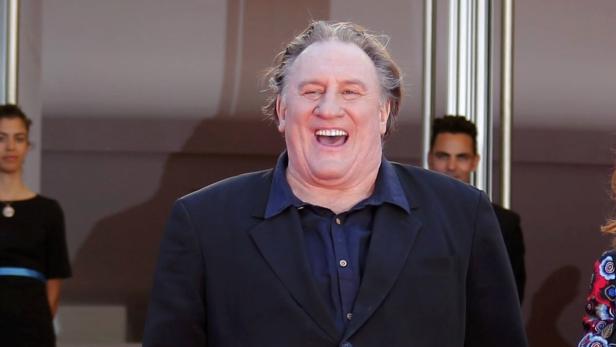 Gérard Depardieu lächelt auf einem roten Teppich.