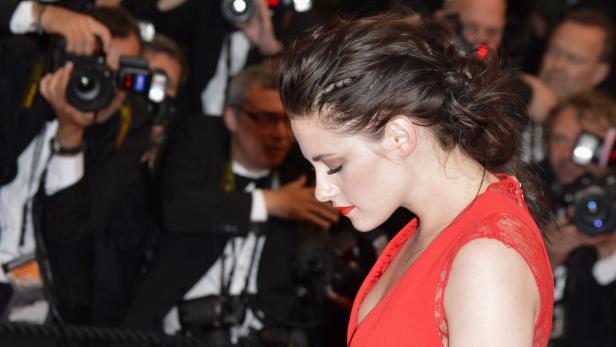 Kristen Stewart in einem roten Kleid vor einer Wand von Fotografen.