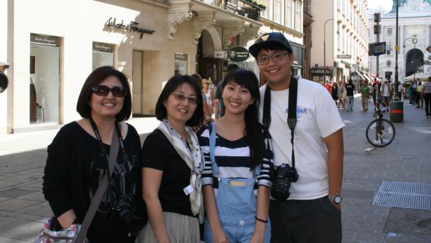 Eine Gruppe von vier Personen posiert vor einem Geschäft in Wien.